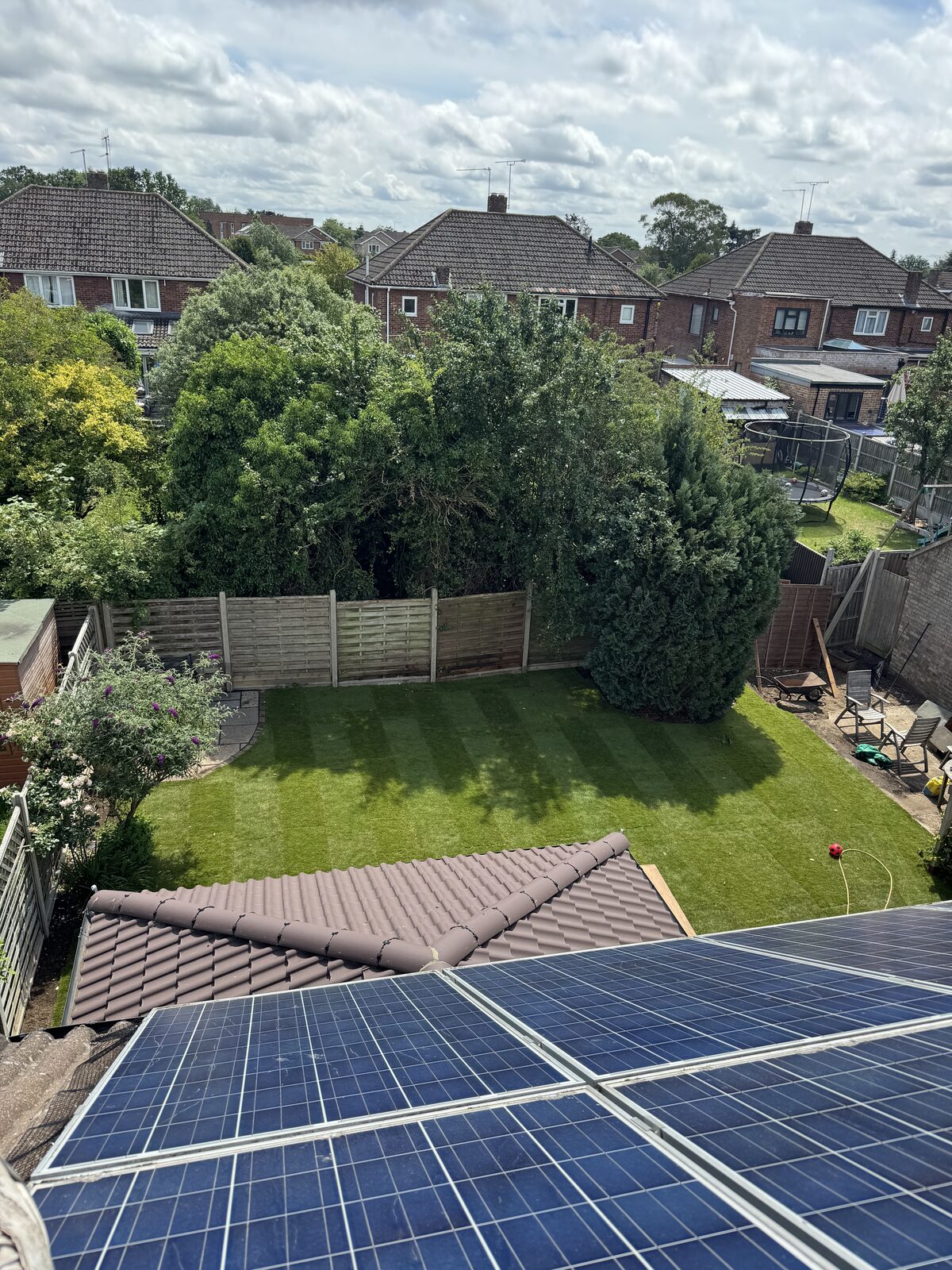 The same rear garden after new turf was laid, showing a freshly mown striped lawn